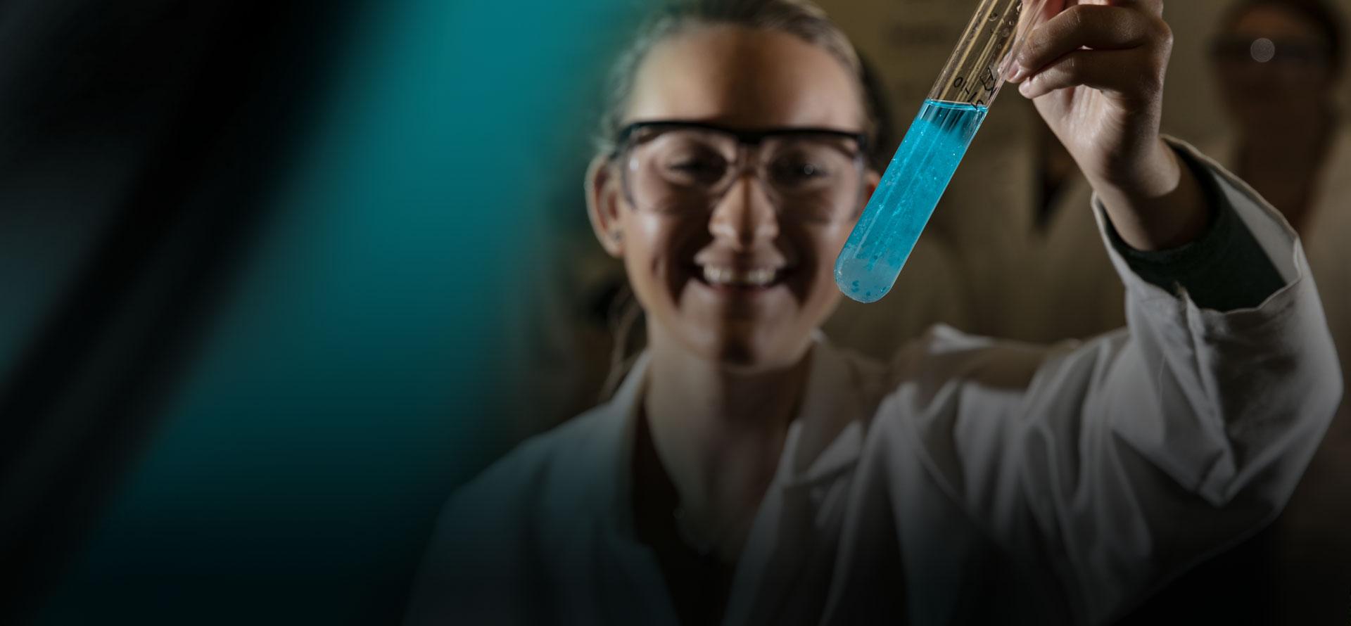 Student holding a test tube on a black and green abstract background
